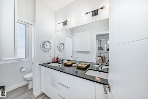 Modern bathroom featuring a dual vanity with white cabinetry and dark countertops - 14812 98 Avenue, Edmonton, AB - Indoor Photo Showing Bathroom