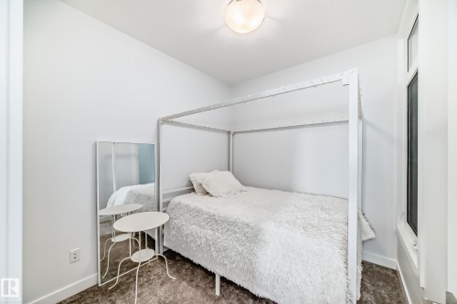 Bright interior space featuring a window, overhead lighting, white walls, and dark wood-finish flooring - 14812 98 Avenue, Edmonton, AB - Indoor Photo Showing Bedroom