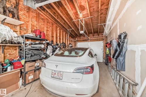 Spacious garage featuring exposed wood framing, concrete flooring, automatic garage door opener, and overhead lighting - 14812 98 Avenue, Edmonton, AB - Indoor Photo Showing Garage