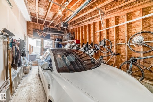Garage space featuring exposed wood framing, an automatic garage door opener, and a rear exit with two windows - 14812 98 Avenue, Edmonton, AB - Indoor