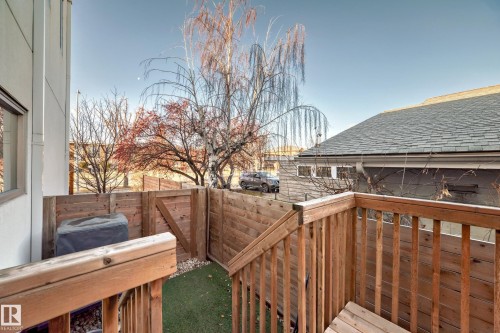 Private outdoor patio featuring wood fencing, artificial turf, and a wood-decked staircase - 14812 98 Avenue, Edmonton, AB - Outdoor