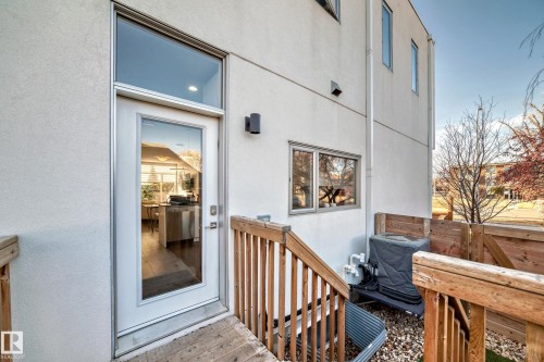 Rear exterior featuring a white stucco facade, full-light door with transom, and a private wooden fence - 14812 98 Avenue, Edmonton, AB - Outdoor With Exterior