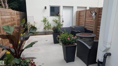 Private patio area featuring concrete paving, horizontal wood fencing, and planted garden beds - 14812 98 Avenue, Edmonton, AB - 