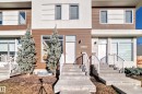 Modern townhouse exterior featuring a white and brown facade, concrete steps with white railings, and mature evergreen trees - 14812 98 Avenue, Edmonton, AB  - Outdoor With Facade 