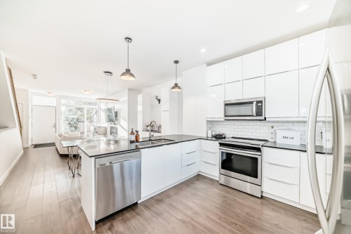 Open-concept kitchen with white cabinetry and dark countertops - 14812 98 Avenue, Edmonton, AB - Indoor Photo Showing Kitchen With Stainless Steel Kitchen With Double Sink With Upgraded Kitchen