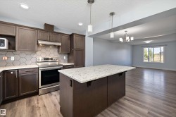 Modern kitchen featuring wood-finish flooring, dark wood cabinetry, white stone countertops, and a gray hexagonal tile backsplash - 