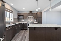 Modern kitchen featuring dark wood-finish cabinetry, stainless steel appliances, and light-toned countertops - 