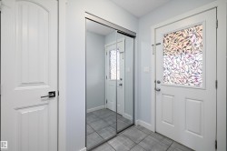 Entryway featuring a white paneled door with decorative glass, tiled flooring, and a mirrored closet door - 