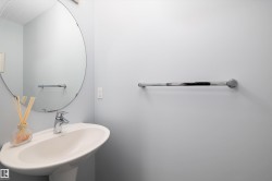 Pedestal sink with chrome faucet, complemented by a large circular mirror and chrome towel bar - 
