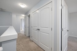 Hallway featuring neutral carpet, light blue wall paint, white trim, and white doors with arched paneling - 