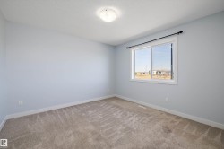 Carpeted room featuring a large window with white trim, light blue walls, and a flush-mount ceiling light fixture - 