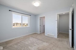 Spacious room featuring light gray walls, plush carpet flooring, and a large window with white trim - 