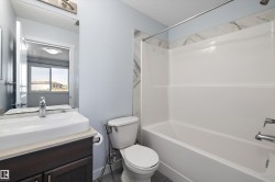 Bathroom featuring a white integrated tub and shower unit with a marble-finish surround - 