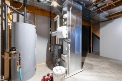 Utility area featuring a water heater, furnace, and exposed ductwork - 