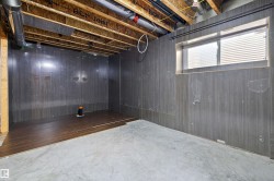 Basement space featuring finished walls, concrete flooring, and a portion of wood-finish flooring - 