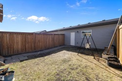 Private backyard space featuring a wood fence, grey siding, and a rear access door - 