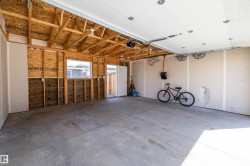 Spacious garage with exposed wood framing, a concrete floor, and an overhead garage door - 