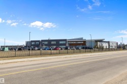 Modern multi-story building featuring a facade of dark gray and light gray panels with large windows - 