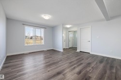 Spacious room featuring wood-finish flooring, light blue walls, a large window, a white paneled door, and a mirrored closet door - 