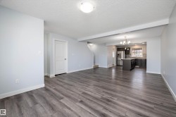 Open-concept living area featuring wood-finish flooring, light-toned walls, and white trim - 