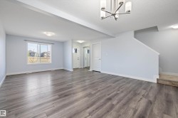 Spacious living area featuring wood-finish flooring, light blue wall paint, and white trim - 