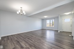 Expansive room featuring wood-finish flooring, white baseboards, and light-toned walls - 