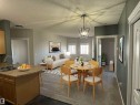 Open-concept living space featuring a dining area with a contemporary chandelier, a kitchen island with an undermount sink, and durable flooring - 224 16807 100 Avenue, Edmonton, AB  - Indoor 
