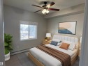 Bedroom featuring a white framed window with blinds, a ceiling fan with light fixture, and neutral gray wall paint - 224 16807 100 Avenue, Edmonton, AB  - Indoor Photo Showing Bedroom 