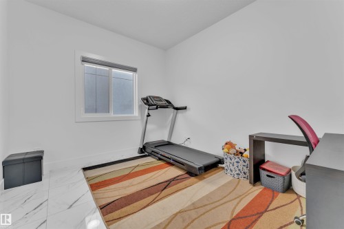White-painted walls with a rectangular window featuring a dark roller shade - 1809 18A Avenue, Edmonton, AB - Indoor Photo Showing Gym Room