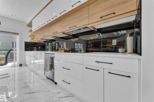 Contemporary kitchen featuring white glossy cabinetry, wood-finish upper cabinets, a black glass backsplash, white countertops, and stainless steel appliances - 1809 18A Avenue, Edmonton, AB - Indoor Photo Showing Kitchen