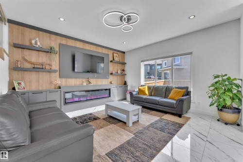 Living area featuring a wood-finish accent wall with an integrated electric fireplace, built-in shelving, and recessed lighting - 1809 18A Avenue, Edmonton, AB - Indoor Photo Showing Living Room