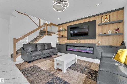 Living area featuring a contemporary built-in media center with a recessed electric fireplace, wood-finish accent wall, and integrated shelving - 1809 18A Avenue, Edmonton, AB - Indoor Photo Showing Living Room With Fireplace