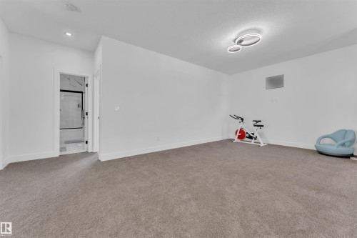 Spacious room featuring neutral carpeting, white walls, and a modern ceiling light fixture - 1809 18A Avenue, Edmonton, AB - Indoor Photo Showing Other Room
