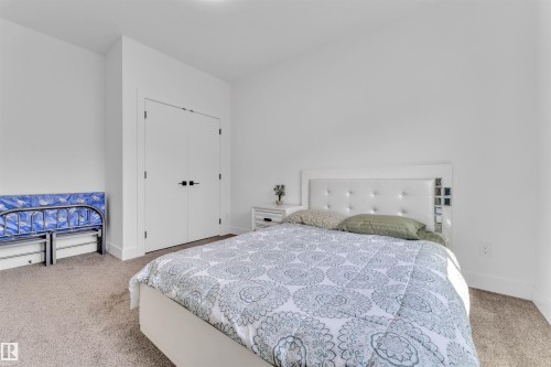 Crisp white walls define this bedroom, featuring a plush carpet, white baseboards, and a built-in closet with double doors - 1809 18A Avenue, Edmonton, AB - Indoor Photo Showing Bedroom