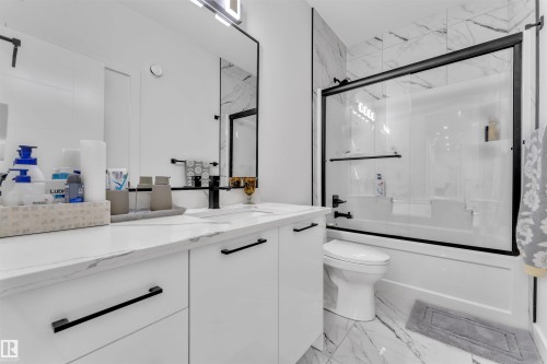 Modern bathroom featuring a white vanity with a marble-patterned countertop, matte black hardware, and a framed mirror with integrated lighting - 1809 18A Avenue, Edmonton, AB - Indoor Photo Showing Bathroom