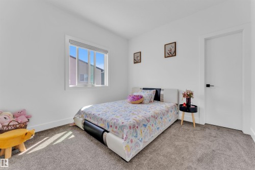 Carpeted room featuring a white interior door with black hardware, a large window, and white baseboards - 1809 18A Avenue, Edmonton, AB - Indoor Photo Showing Bedroom