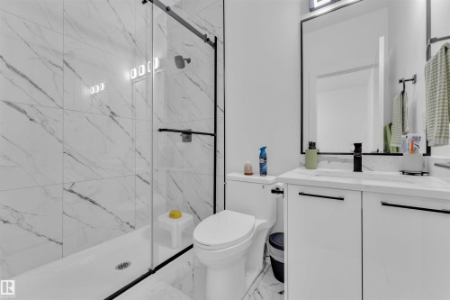 Contemporary bathroom featuring a spacious walk-in shower with a black-framed glass enclosure, full-height marble-finish tile, and a black showerhead - 1809 18A Avenue, Edmonton, AB - Indoor Photo Showing Bathroom