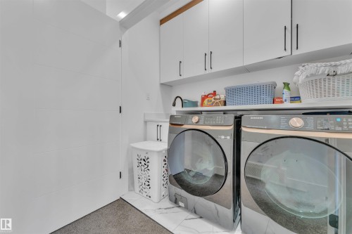 Dedicated laundry area featuring a white shaker-style cabinetry, dark hardware, and a white countertop - 1809 18A Avenue, Edmonton, AB - Indoor Photo Showing Laundry Room