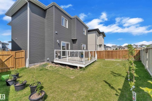 Spacious backyard featuring a low-maintenance deck with glass panel railings, a manicured lawn, and privacy fencing - 1809 18A Avenue, Edmonton, AB - Outdoor With Deck Patio Veranda