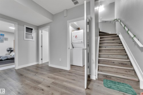 Wood-finish flooring throughout, bright gray walls, white trim, recessed lighting, and a stackable washer and dryer unit - 1809 18A Avenue, Edmonton, AB - Indoor