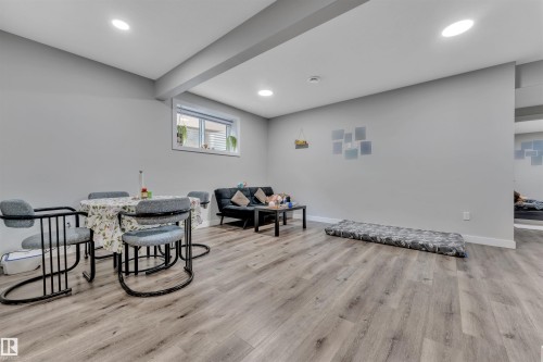 Open-concept living area featuring light gray walls, wood-finish flooring, and recessed ceiling lighting - 1809 18A Avenue, Edmonton, AB - Indoor