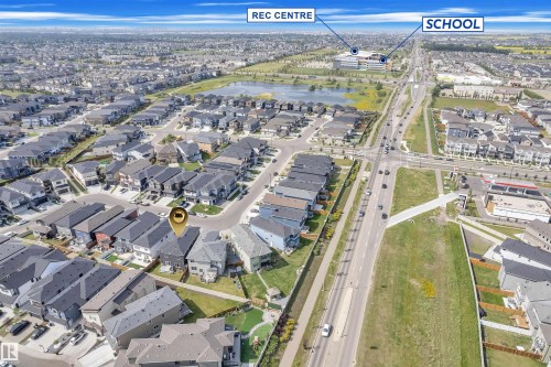 Aerial view of a residential community with numerous single-family homes and townhomes, featuring a prominent road network, a nearby recreational center, and a school - 1809 18A Avenue, Edmonton, AB - Outdoor With View