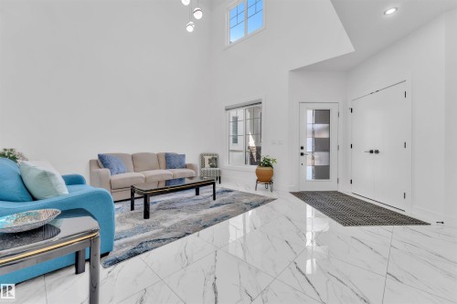 Entryway with high ceilings, large format marble-look tile flooring, and a contemporary glass panel door - 1809 18A Avenue, Edmonton, AB - Indoor