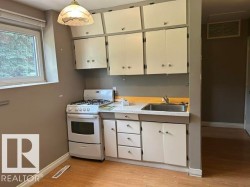 Compact kitchen featuring a gas range, stainless steel sink, and wood-finish flooring - 