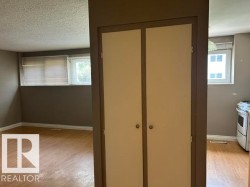 Built-in storage cabinet with two doors, flanked by rooms featuring wood-finish flooring, neutral wall paint, and white trim - 