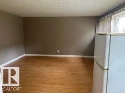 Spacious room featuring wood-finish flooring, neutral-toned walls, and white baseboards - 