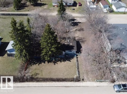 Expansive lot featuring mature trees, a manicured lawn, and paved street frontage - 5010 50 Street, Ardmore, AB 