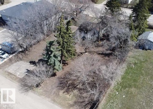 Expansive lot featuring mature trees, a detached storage building, and a concrete pad - 5010 50 Street, Ardmore, AB 