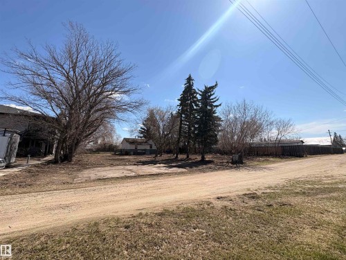Expansive property with mature trees, established fencing, and visible utilities for development - 5010 50 Street, Ardmore, AB 