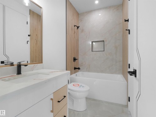 Modern bathroom featuring a single vanity with a white countertop and integrated sink, matte black faucet, and wood-finish cabinetry - 2070 Collip Crescent, Edmonton, AB - Indoor Photo Showing Bathroom
